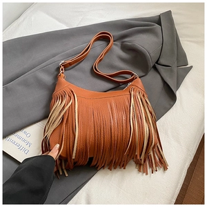 Close-up of caramel brown leather shoulder bag featuring tassel detail and lychee texture