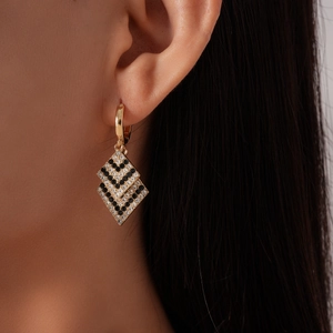 Detailed close-up of geometric gold drop earrings with black and white rhinestones