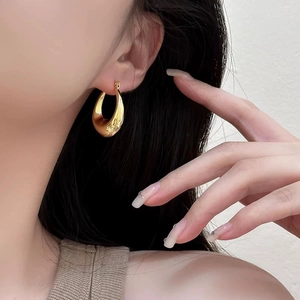Minimalist thick gold geometric U-shaped hoop earrings on model with high gloss finish