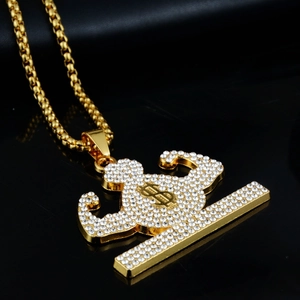 Macro detail of gold-toned muscular arm pendant with rhinestones and dollar sign
