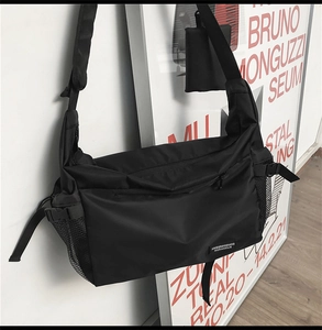 Macro detail of black nylon crossbody bag with adjustable wide strap and side mesh pocket
