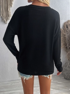 Vue arrière du pull en maille noire ample avec une texture fine et manches longues