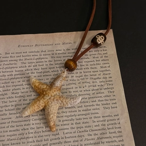 Close-up of a starfish pendant with wooden beads and ethnic patterns on vintage paper