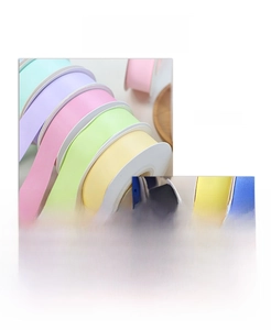 Detailed macro view of multiple macaron-colored polyester satin ribbon rolls for gift wrapping