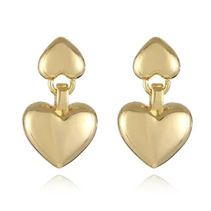 Close-up of double heart drop earrings with a polished gold-plated metallic finish