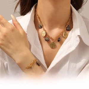 Detail of vintage gold necklace and bracelet set with religious charms on a white shirt