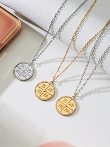 Makroaufnahme von Edelstahl-Münzanhängern mit Kreuz und griechischen Symbolen