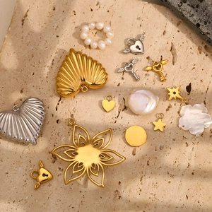 Detailed view of 18K gold plated angel key and heart charms on a stone surface