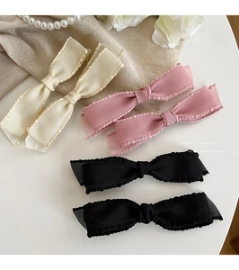 Detailed set of bow hair clips in white, pink, and black colors with ribbed texture