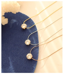 Detailed view of three 18K gold-plated vertical chain necklaces with 4-prong zircon pendants