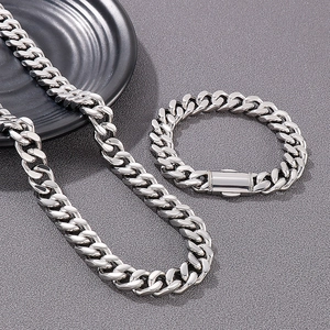 Detailed view of silver mens cuban link necklace and bracelet set on dark texture