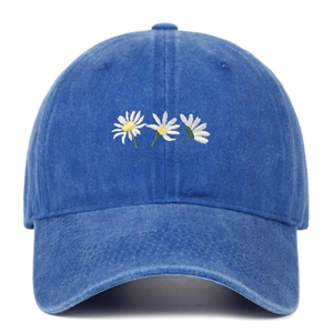 Dettaglio del ricamo a margherita bianca su cappello in cotone lavato blu di qualità