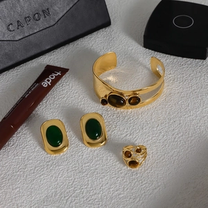 Tiger eye open bangle with green emerald studs and hollow stone ring set on white marble