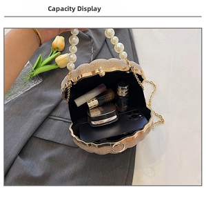 Interior view of shell-shaped evening bag showing smartphone, lipstick, and perfume