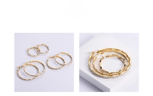 Macro detail of three-size set of golden wave-shaped hoop earrings with inlaid zircons