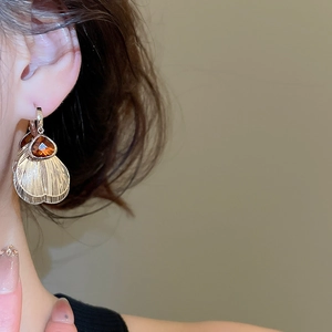 Close-up of model wearing vintage fan-shaped earrings with amber crystal drops