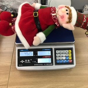 Poupée de Noël elfe en peluche pesée sur une balance électronique de précision