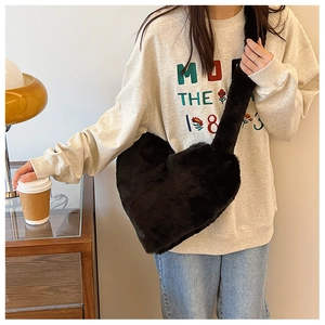 Model wearing a black heart-shaped faux fur plush shoulder bag with matching soft strap