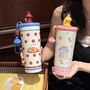 Detail of cute stainless steel thermos with straw lid and decorative charms