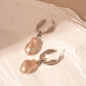 Détail de boucles d'oreilles perles champagne irrégulières sur fond de pierre minérale blanche