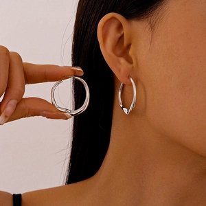 Minimalist silver irregular geometric hoop earrings with polished metallic finish on model