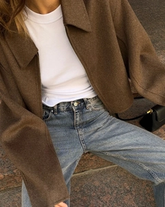 Detailed close-up of a brown cropped wool jacket paired with blue high-waist denim jeans