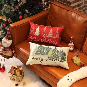 Christmas linen throw pillows with festive tree prints on a cozy leather sofa