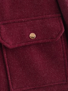 Detailaufnahme der dunkelweinroten Tweedjacke mit goldenem Metallknopf und Pattentasche