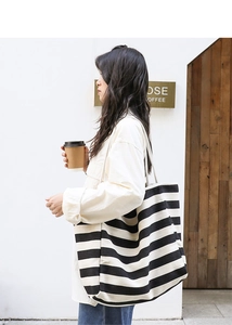 Outdoor model showing the drape of black and white striped canvas tote bag in high detail