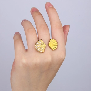 Gros plan d'une bague ouverte dorée 18 carats avec motif coquillage et perles sur le doigt