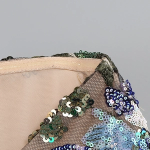 Close-up of champagne sequins and army green embroidery on mesh cocktail dress fabric