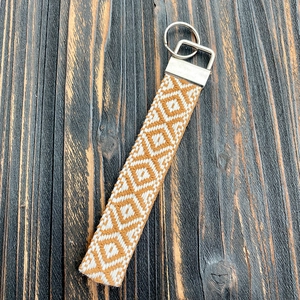 Detail of bohemian orange and white woven lanyard on a rustic wooden surface