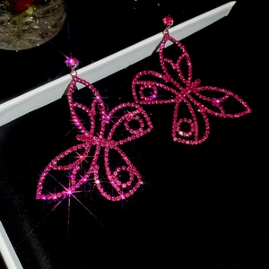 Detail of rose pink butterfly drop earrings with sparkling crystals on black velvet
