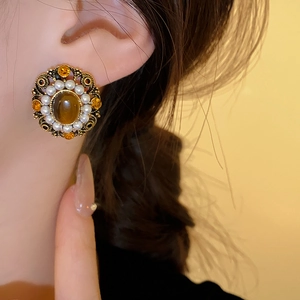 Close-up of vintage bronze earring with brown gemstone, pearls, and amber stones detail