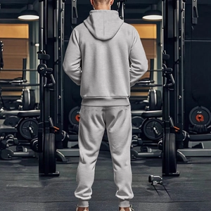 Survêtement homme gris avec sweat à capuche et pantalon de jogging dans une salle de sport