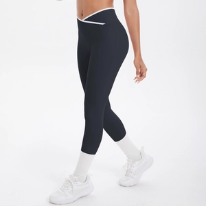 Détail de la taille croisée en V avec liseré blanc sur un legging de yoga noir gainant