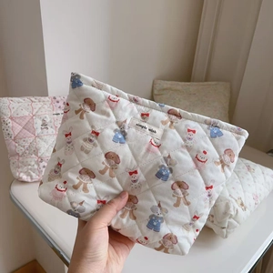 Detailed macro view of quilted cream fabric featuring cute cartoon animals and simple wish label