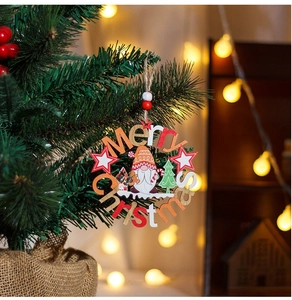 Close-up of wooden Merry Christmas gnome wreath hanging on a festive Christmas tree branch