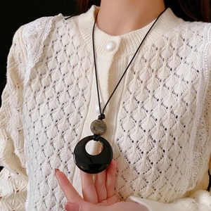 Minimalist geometric agate necklace featuring black circle pendant and marble bead on a model