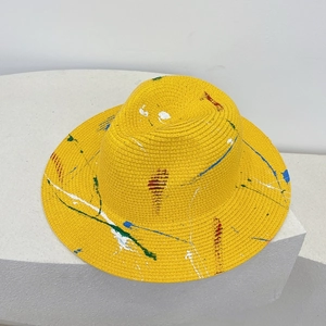 Macro detail of hand-painted colorful ink graffiti on a yellow straw panama jazz hat