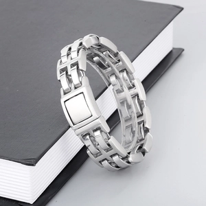 Macro detail of silver stainless steel link bracelet with rectangular clasp on black book