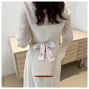 Détail du sac seau en paille avec base en cuir, décor de foulard et chaîne argentée