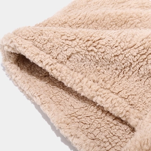 Close-up of soft beige sherpa fleece fabric showing premium warm texture and stitching