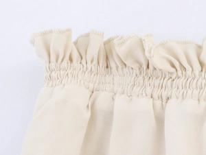 Detail of layered ruffle elastic cuffs and woven fabric texture on beige midi dress