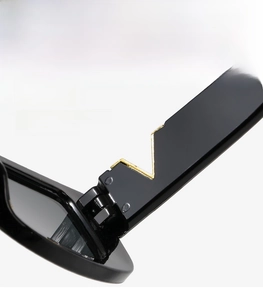 Detail of sturdy hinge on black sunglasses featuring a polished gold V-shaped metal accent