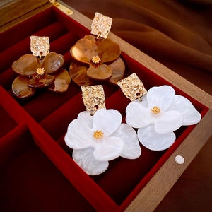 Detail of flower earrings in amber and cream resin with hammered gold metal studs