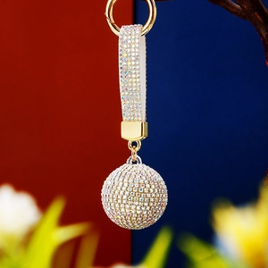 Detail of a sparkling crystal-studded ball keychain with white leather strap on metal ring