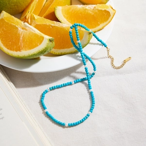 Close-up of blue turquoise and white pearl beaded necklace with gold clasp on linen