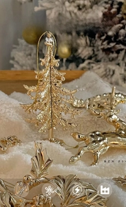 Detailed view of golden Christmas ornaments featuring reindeer and trees on snow
