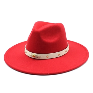 Detail of dark red wool fedora featuring a beige leather band with gold studs and bow